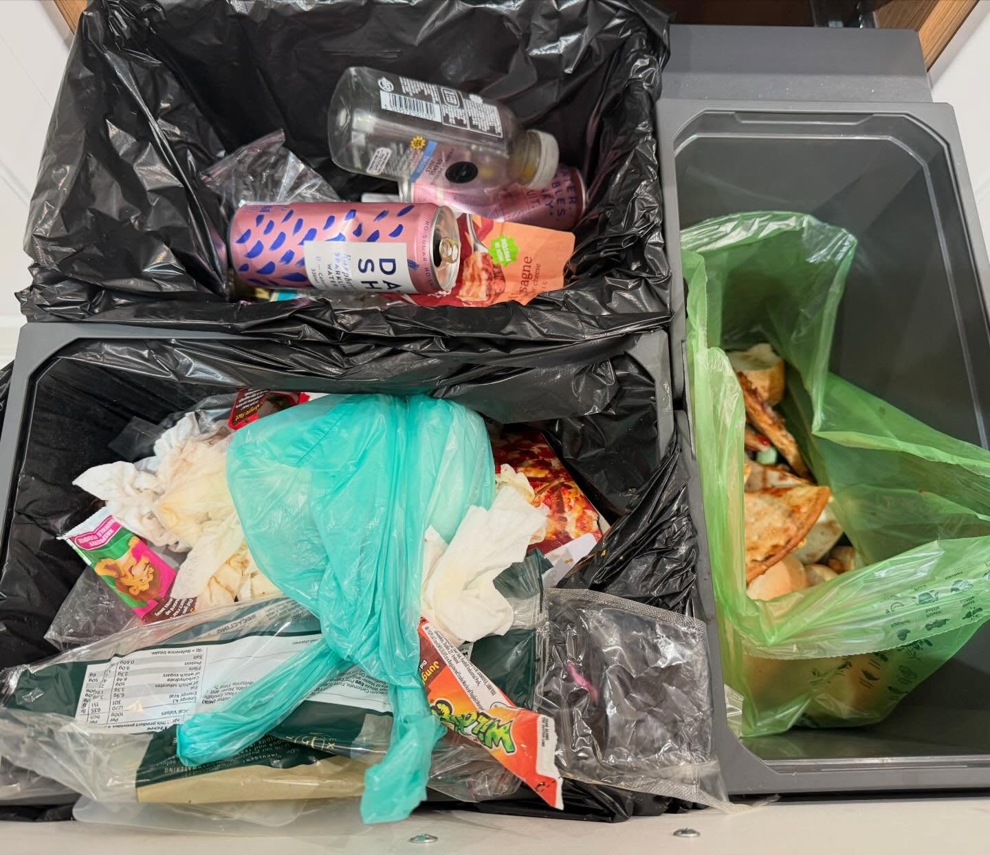 Kitchen bin cupboard before organising, with overflowing waste and recycling